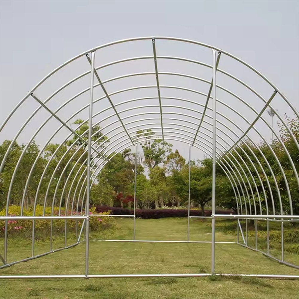 Steel arch frame of a polytunnel greenhouse on a grass site