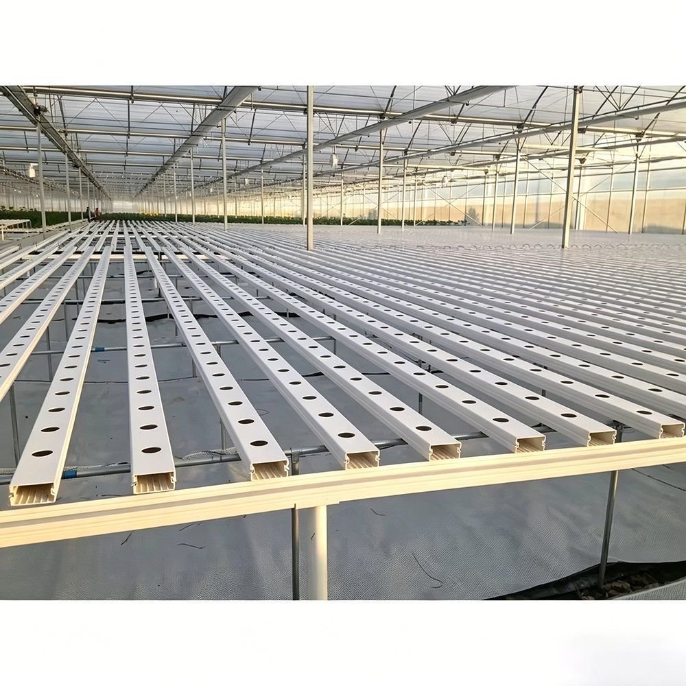 Hydroponic growing channels laid out in rows under a greenhouse frame