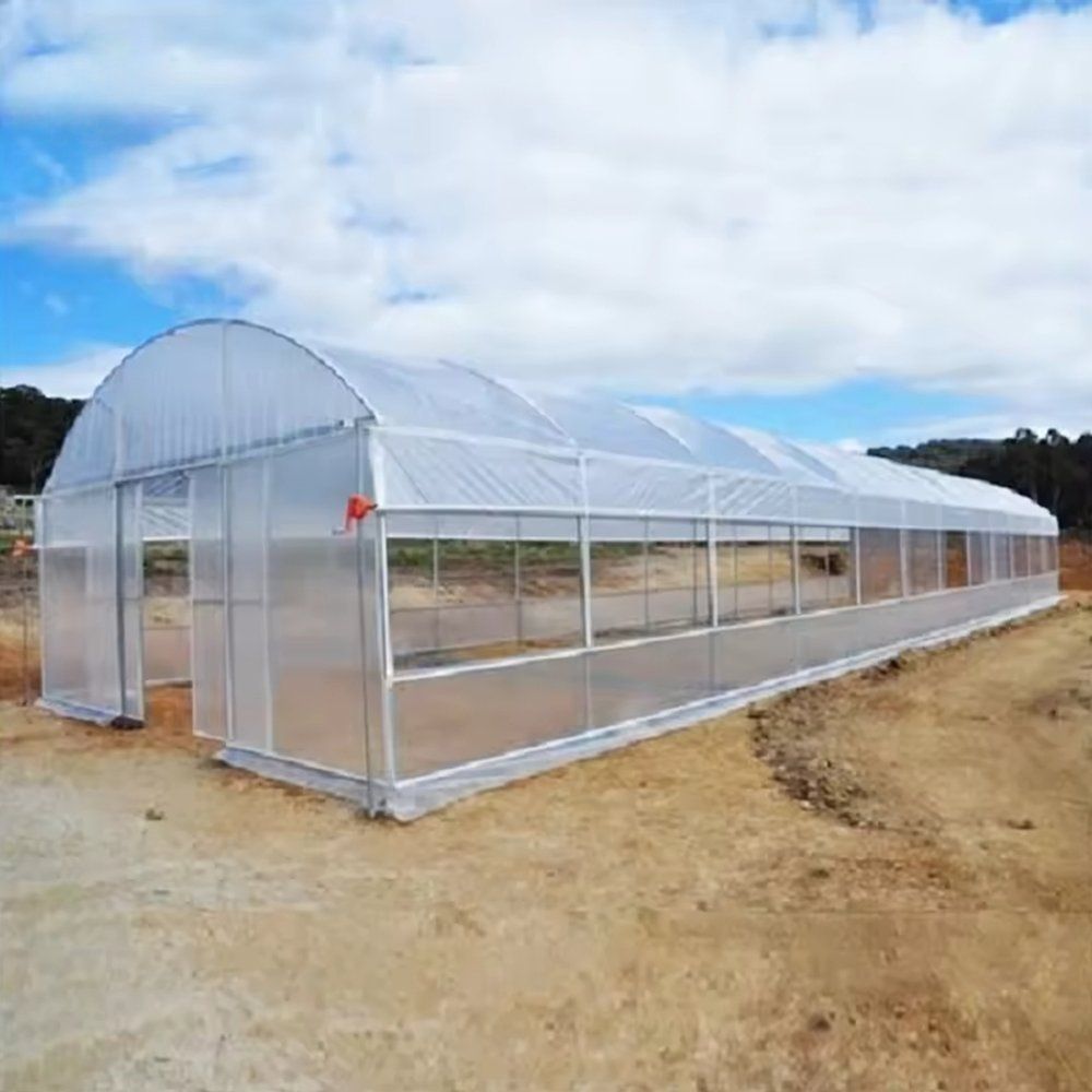 Galvanized steel hoop frame of the polytunnel greenhouse seen from the side under a blue sky