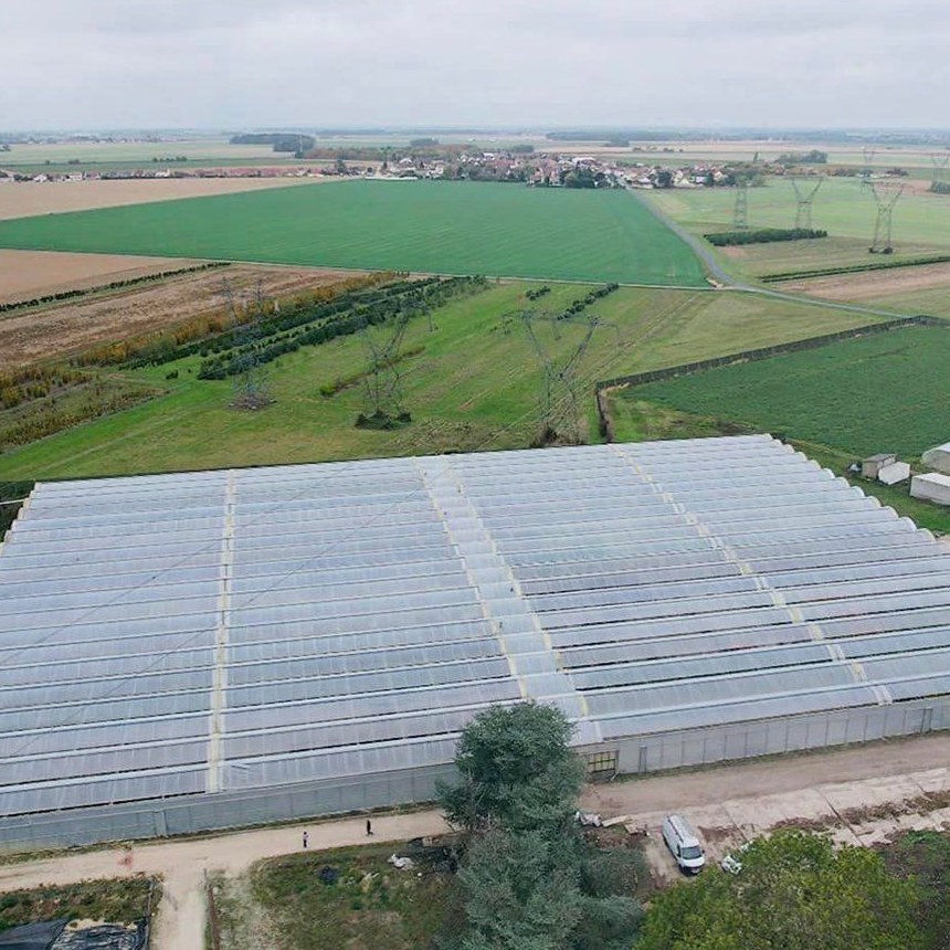 Aerial view of a multi span film greenhouse range across open farmland