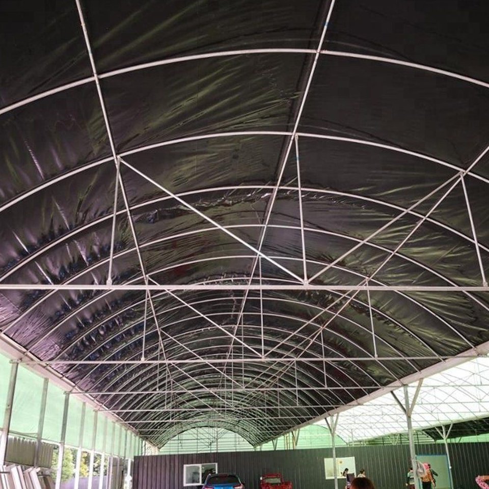 Growing beds under shade netting inside a covered greenhouse