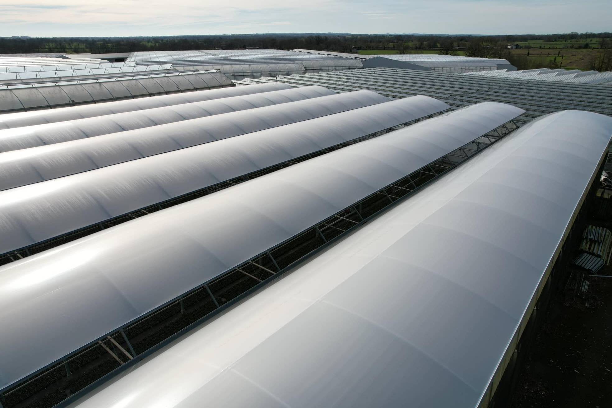 Aerial view along the arched film roofs of a multi span greenhouse