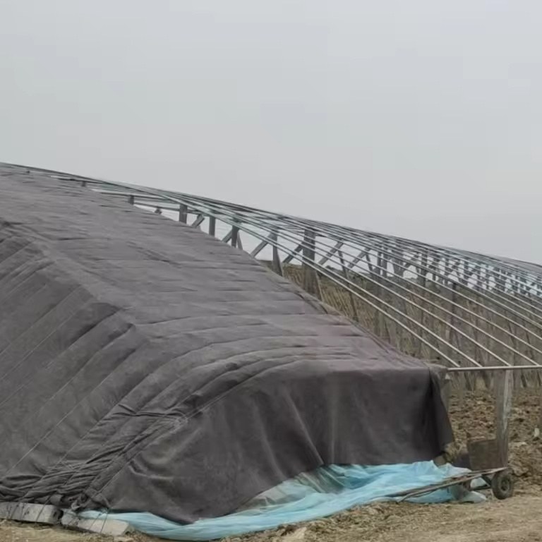 Grey shade netting laid over the arch frame of a high tunnel greenhouse