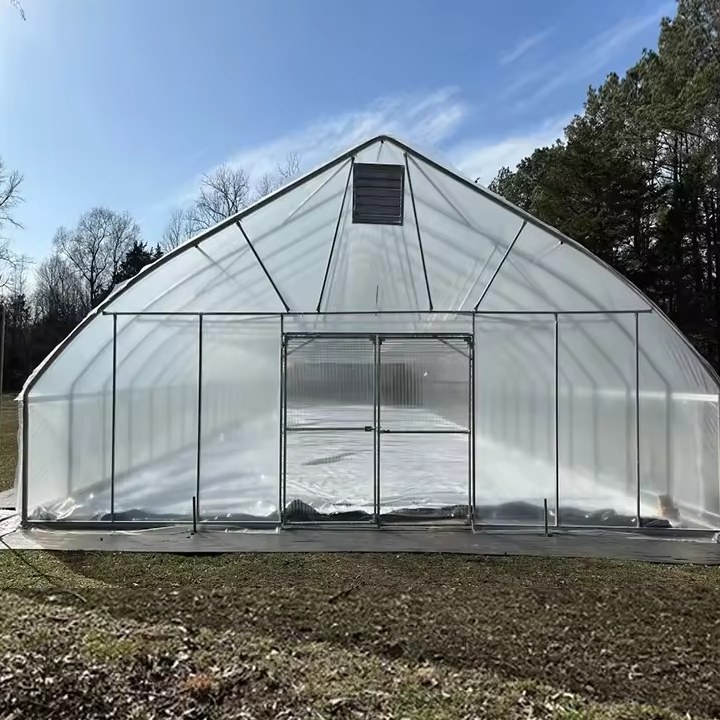 Front view of a single span film tunnel greenhouse with an arched roof and end door
