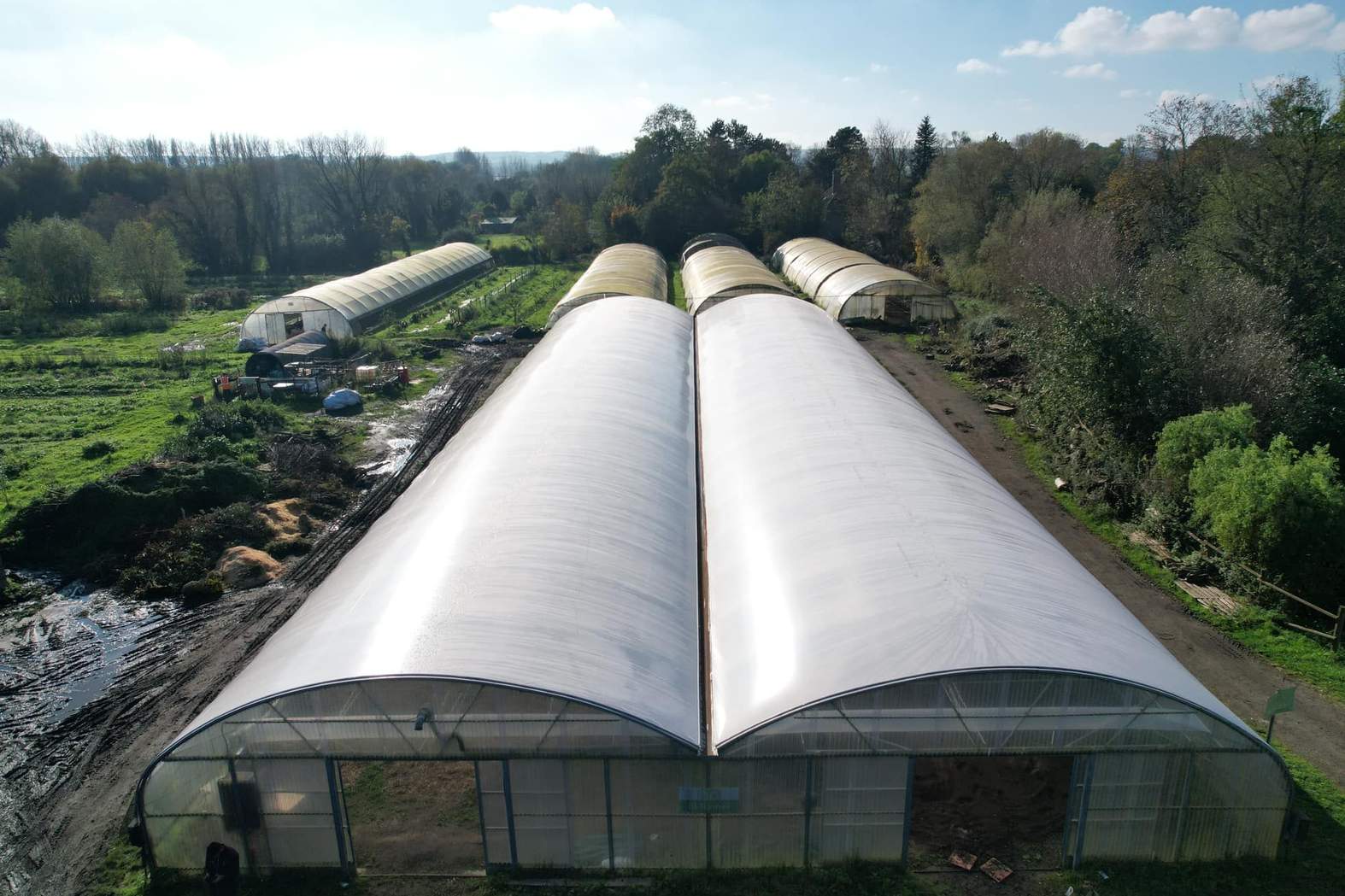 Multi span film greenhouses laid out on a farm with fields beyond