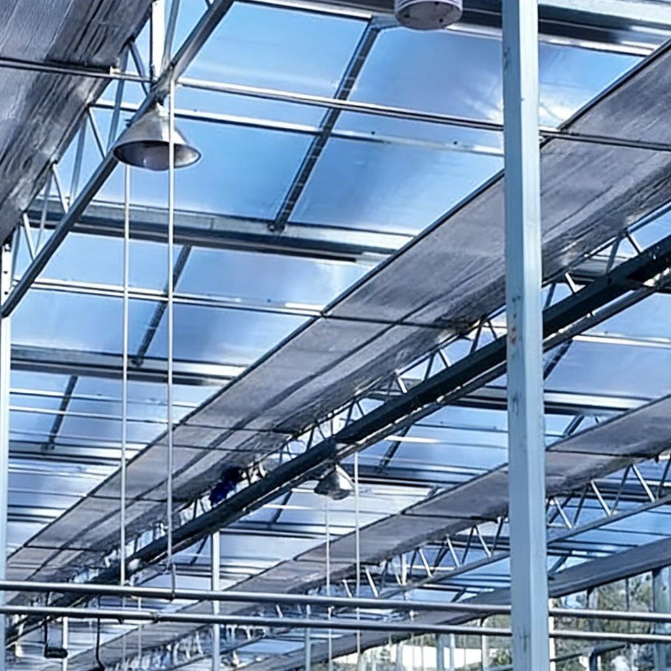 Greenhouse roof with ventilation fans and air distribution ducts above the crop