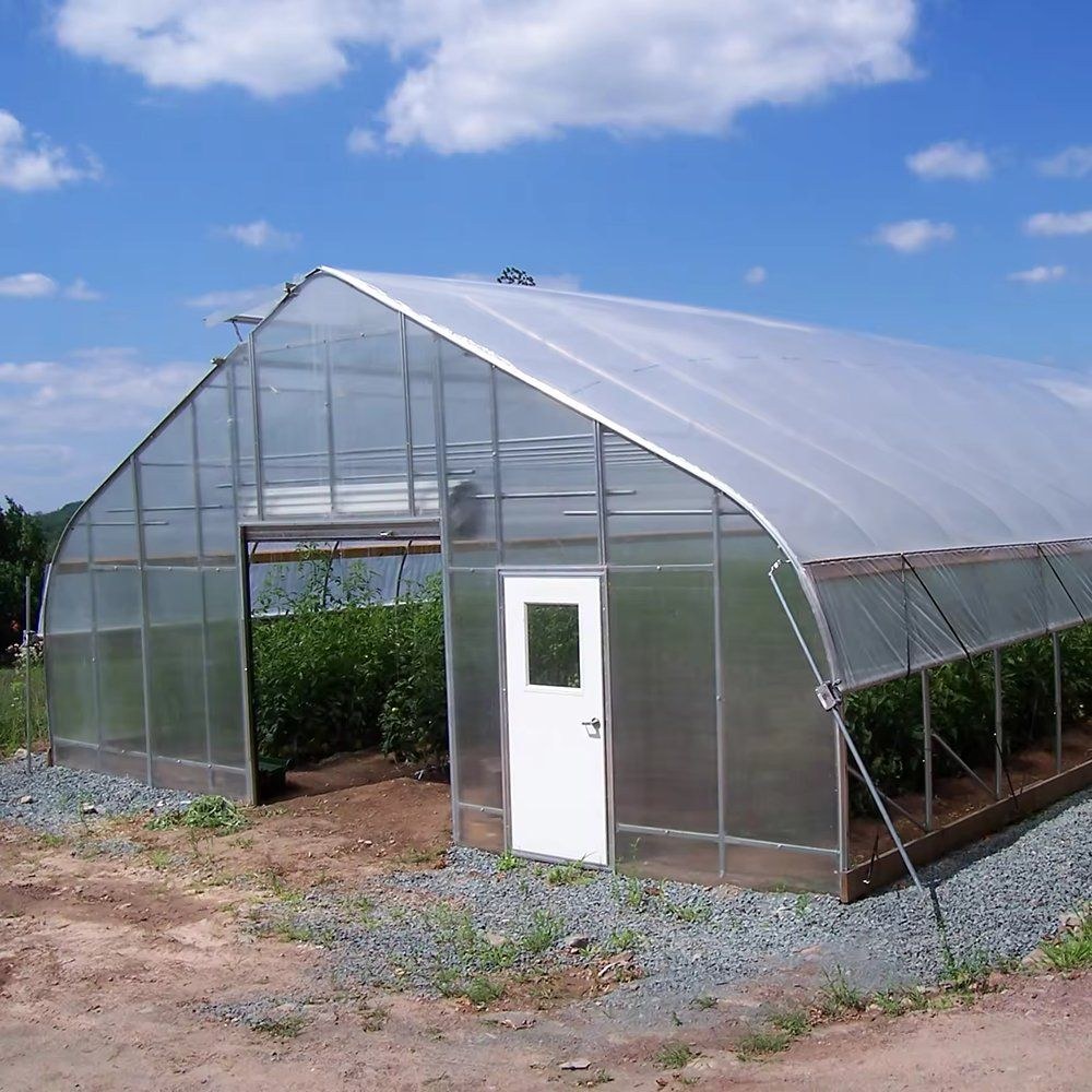 Small gable greenhouse with a white door under a blue sky