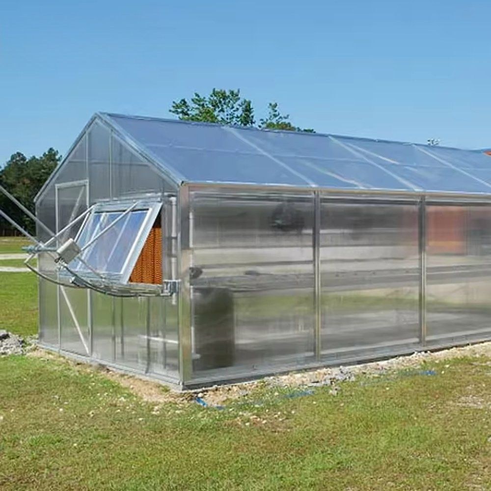 Gable greenhouse with a vent window open and trees behind