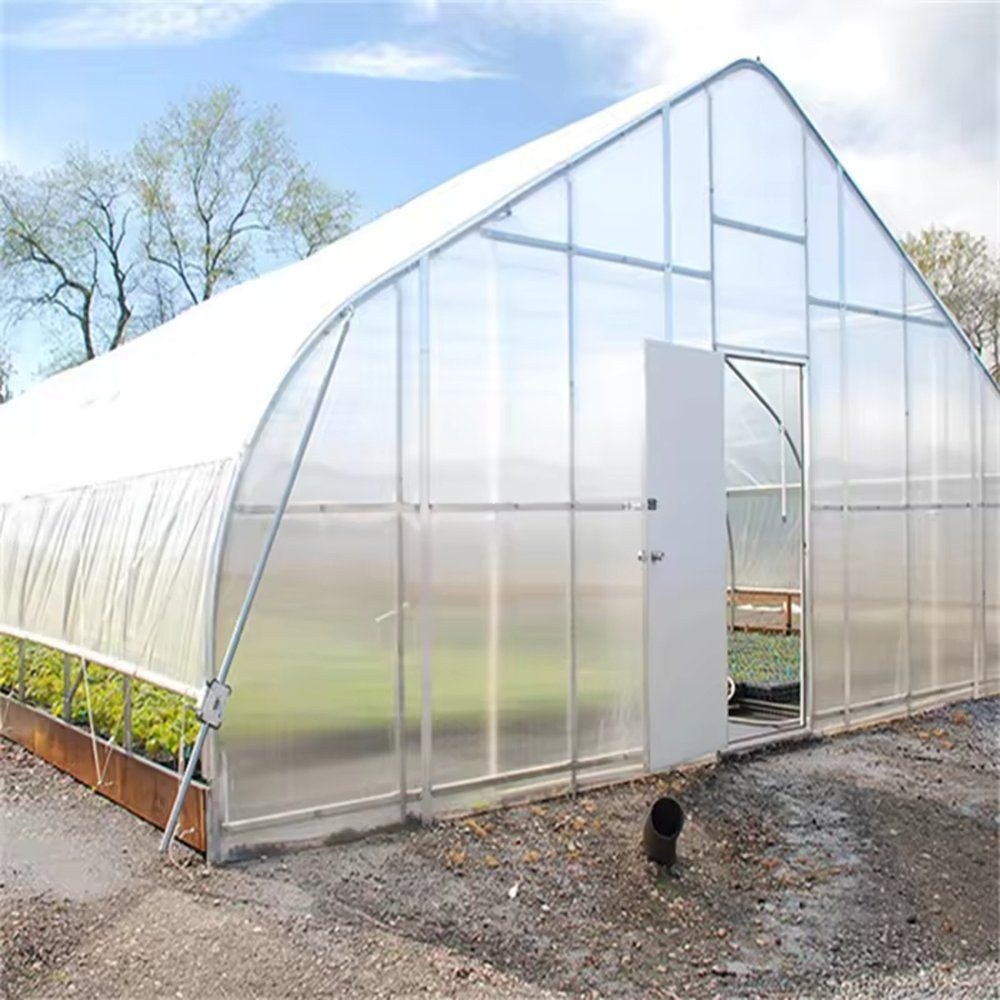 Gothic arch greenhouse with the door open on a gravel apron