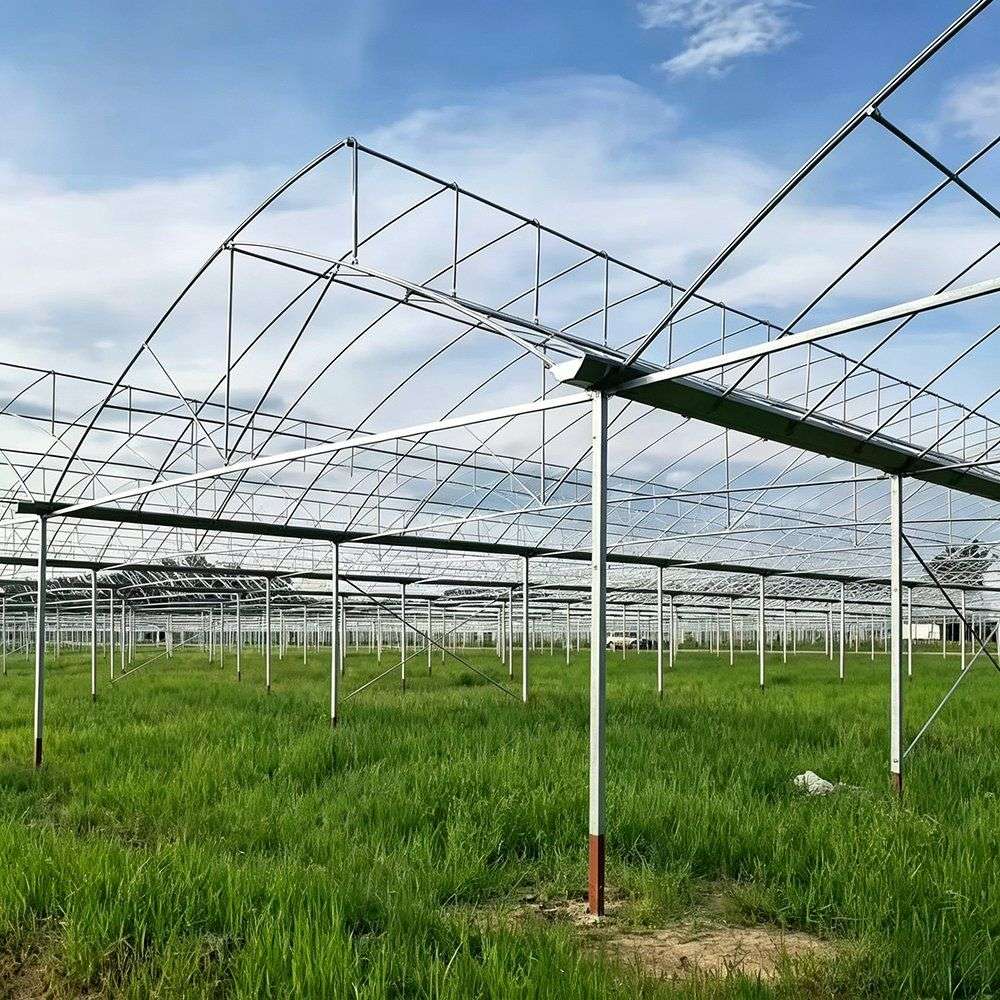 Steel greenhouse frame sections laid out on a yard before assembly