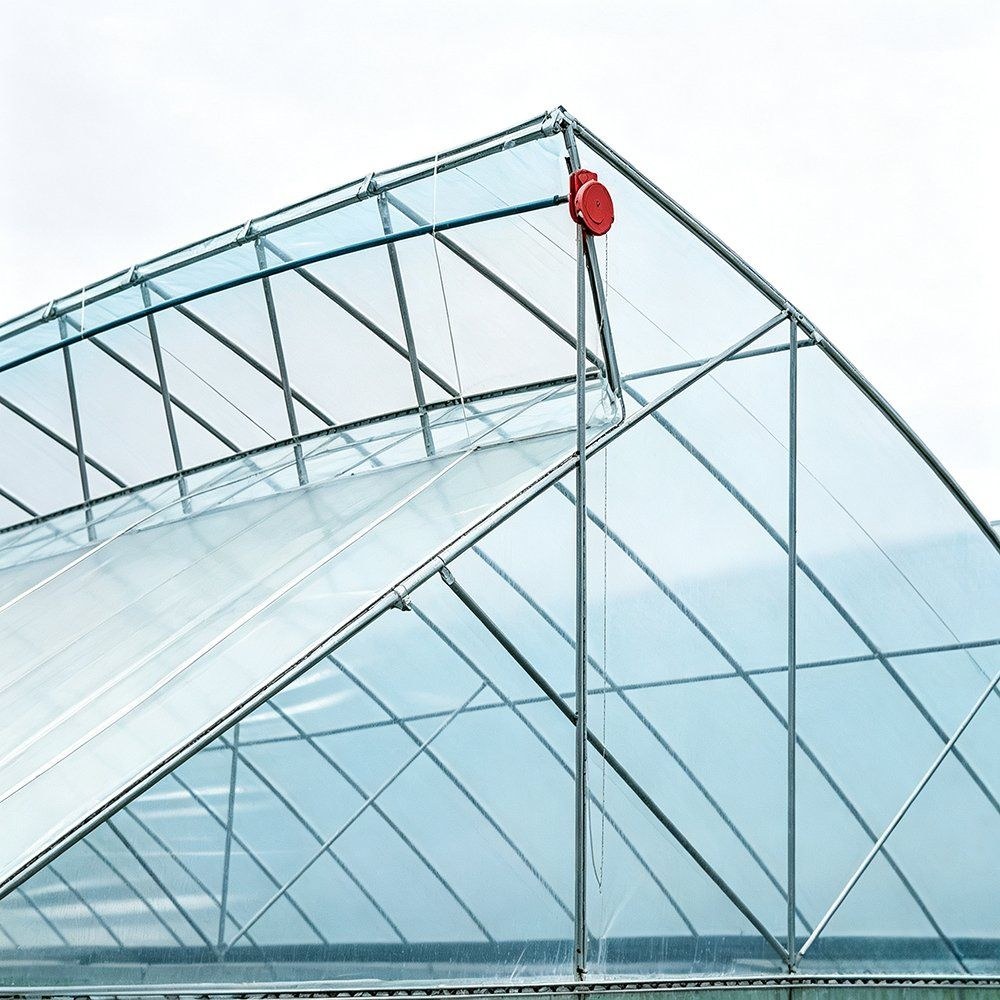 Gothic roof greenhouse frame with a red roll up film winder