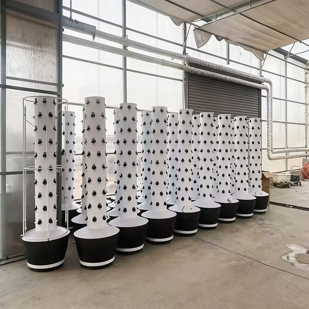 White hydroponic towers standing in a greenhouse with a concrete floor
