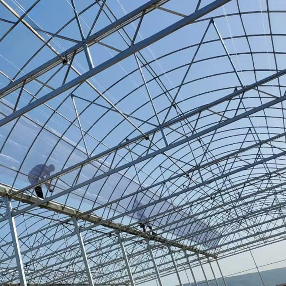 Roof frame of the multi span greenhouse with a worker on the structure