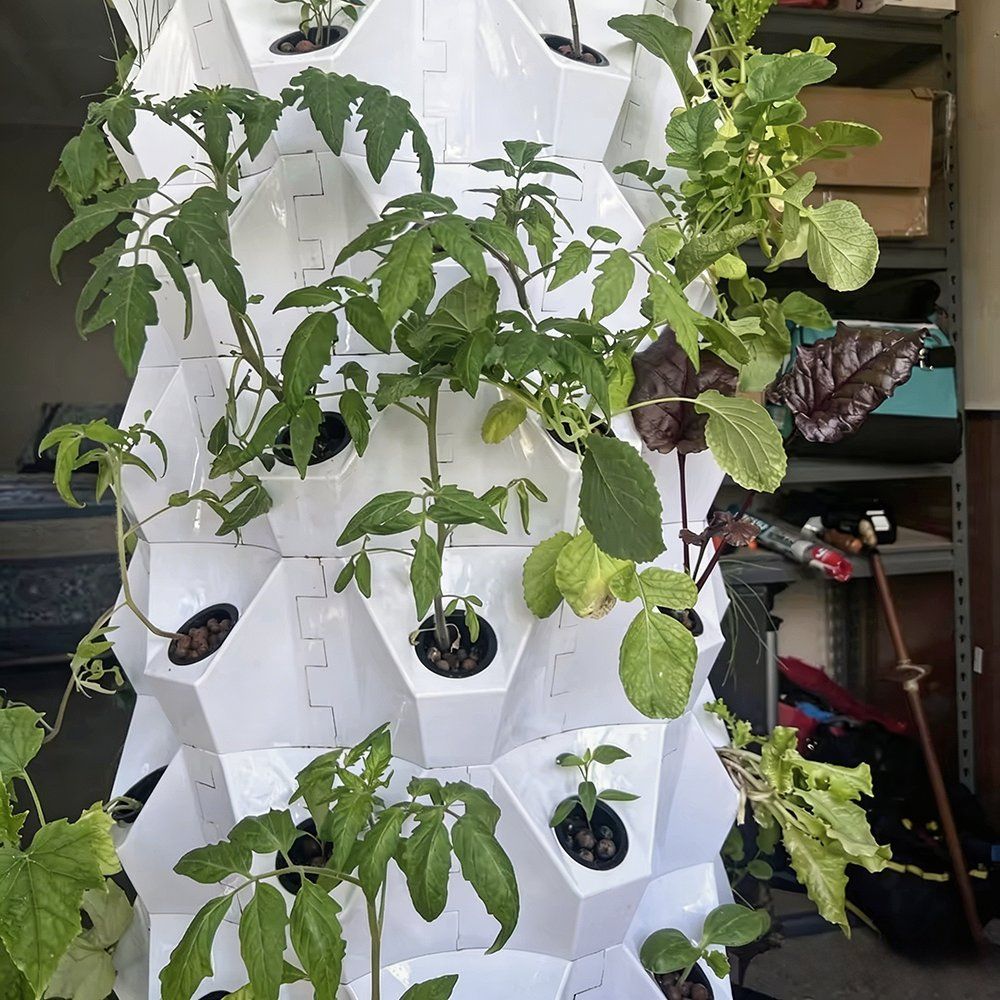 Plant tower with tomato and pepper plants growing from the growing ports