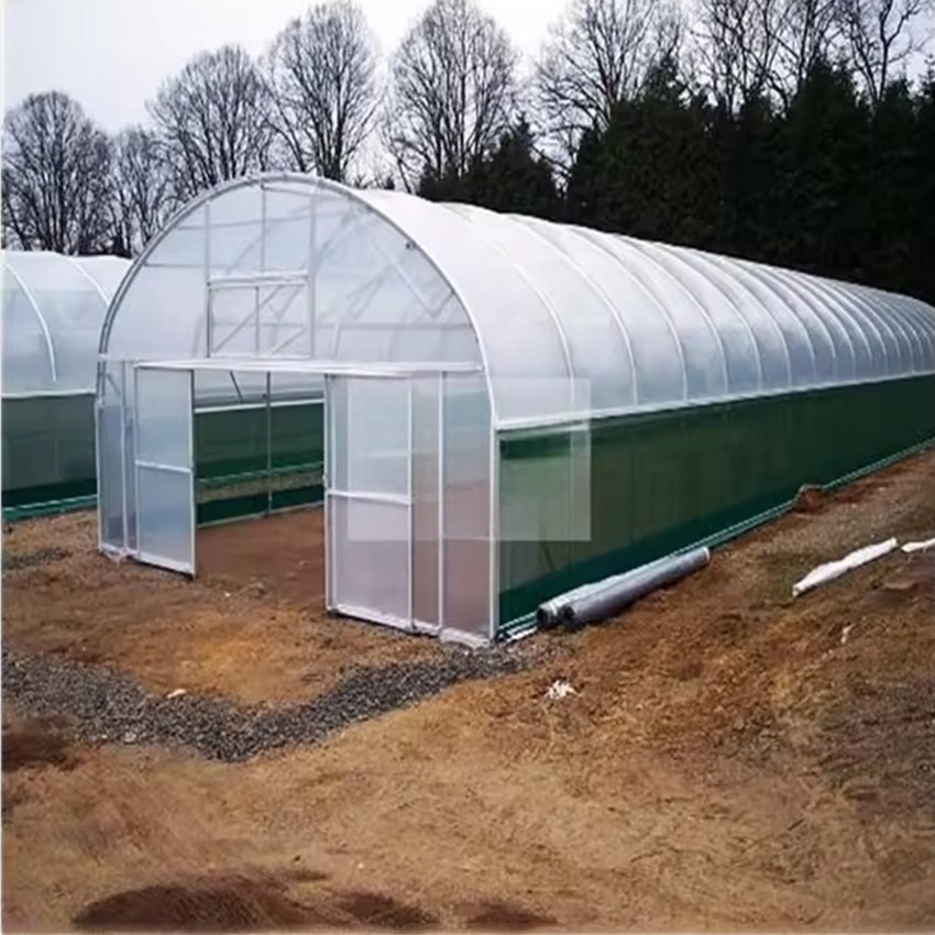 Arched greenhouse kit with pipework and fittings laid out on site