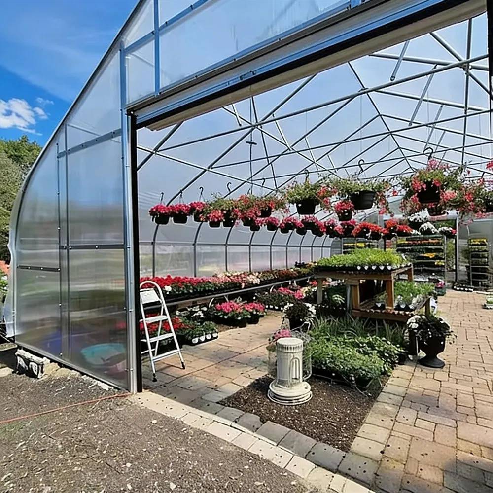 Entrance of a film covered greenhouse with flowering plants displayed at the doorway