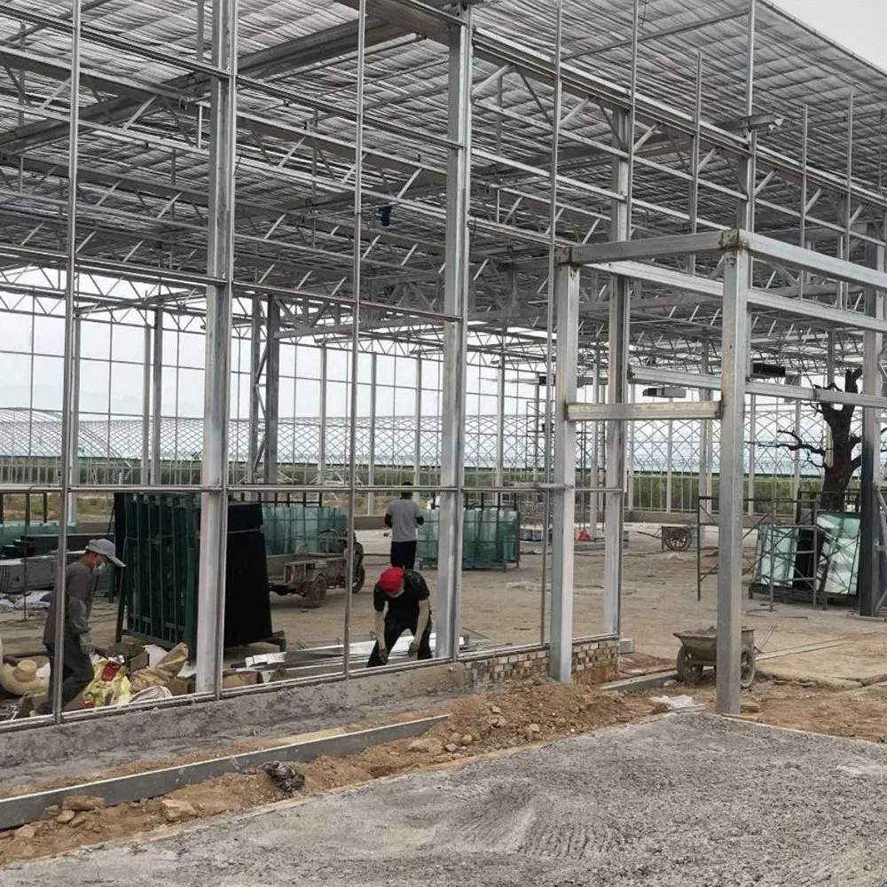 Workers assembling the galvanized frame of a glass greenhouse on site