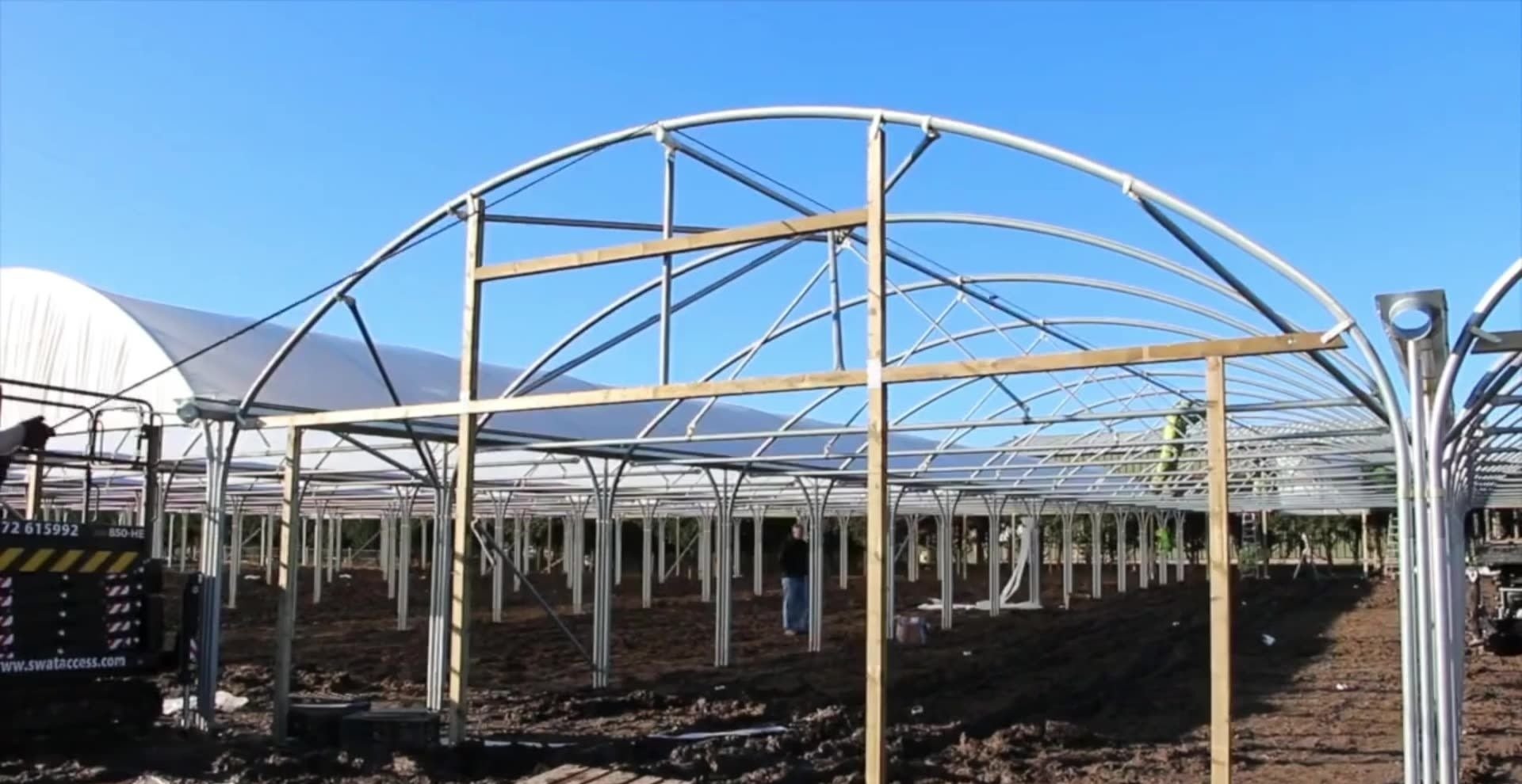 Hoop house greenhouse on a farm track with open fields behind