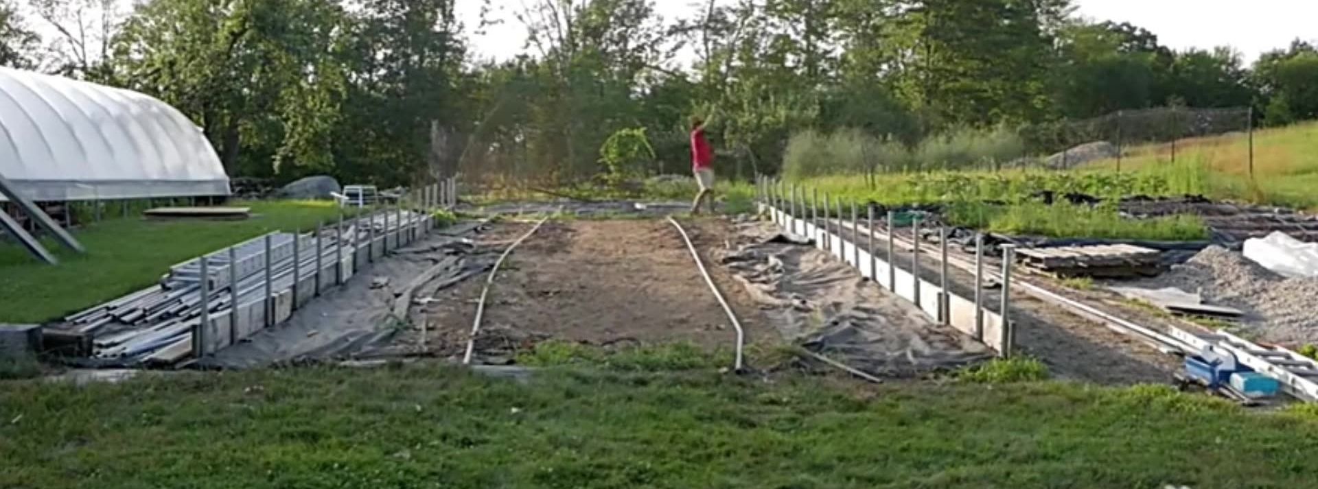 Tunnel greenhouse frame being erected on a prepared site