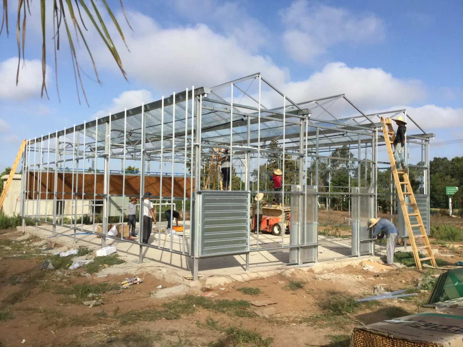 Greenhouse construction site with frames, materials and workers